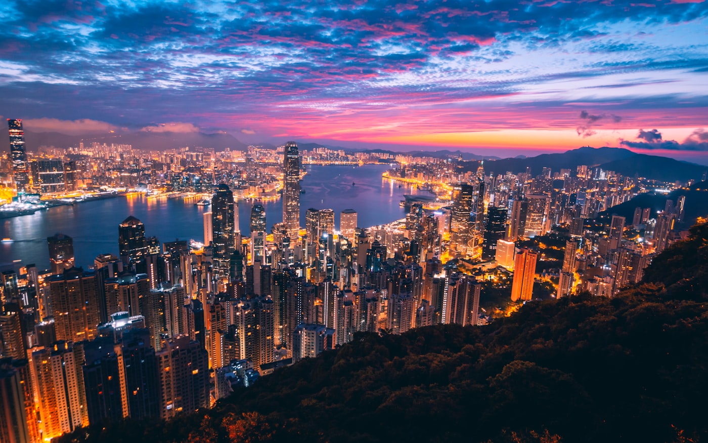 The iconic, incredibly dense neon-lit skyline of Victoria Harbour viewed from Victoria Peak at twilight