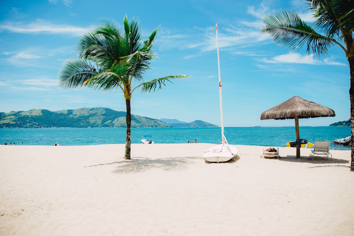 A traditional Thai longtail boat resting on the flawless white sand of a secluded Phuket beach against turquoise waters