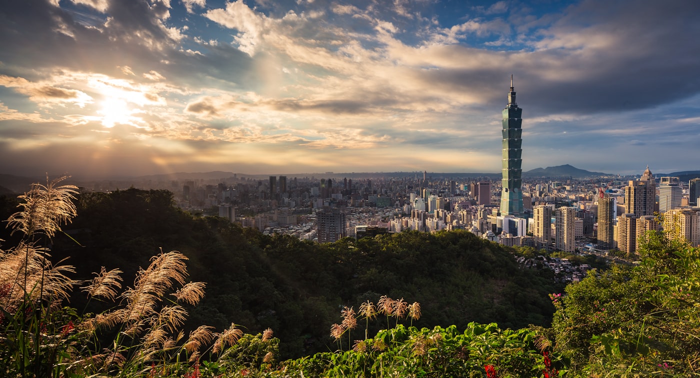 The bamboo-inspired architecture of Taipei 101 towering over the densely populated, neon-lit streets of the Xinyi District