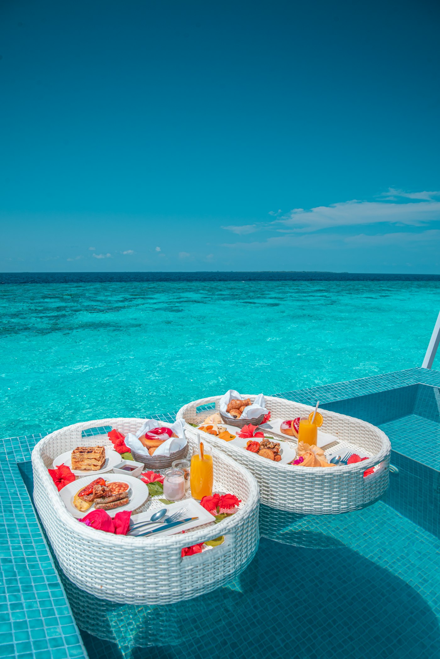 A traditional wooden dhow boat floating on turquoise water off a white sand beach